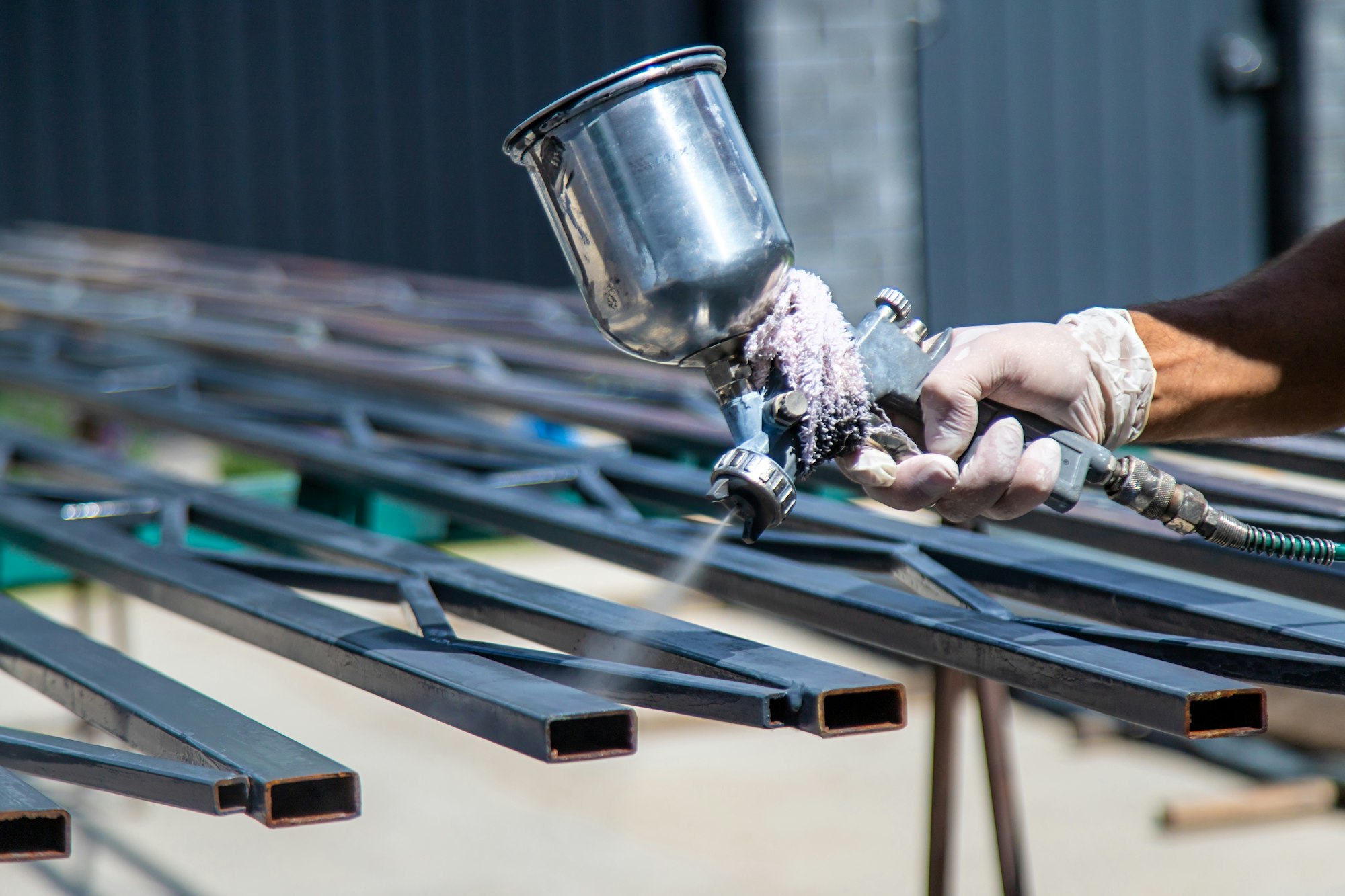 A man spray paints metal. Selective focus.