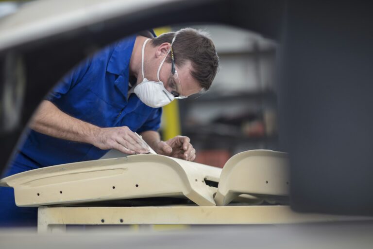 Car mechanic sanding car door in repair garage