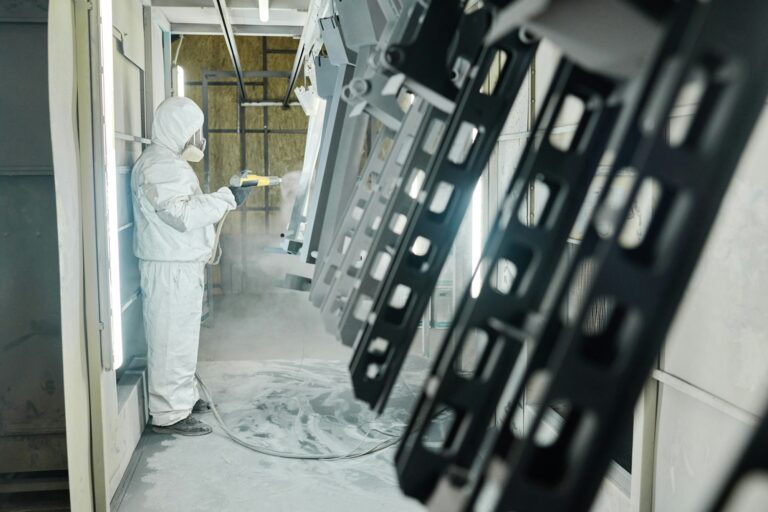 Man painting metal products with spray gun